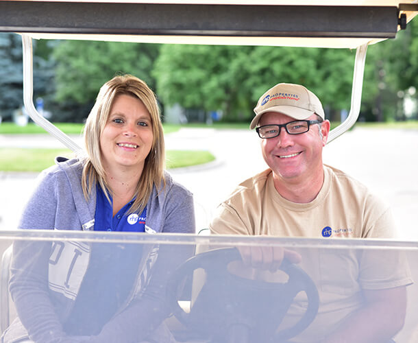 a woman and man smiling and sitting together on a golf cart in a manufactured community near me