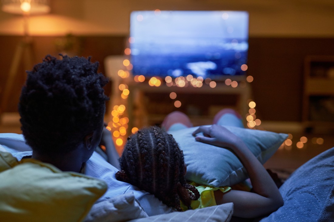 Family watching a movie together in a cozy manufactured home living room with blankets and popcorn.
